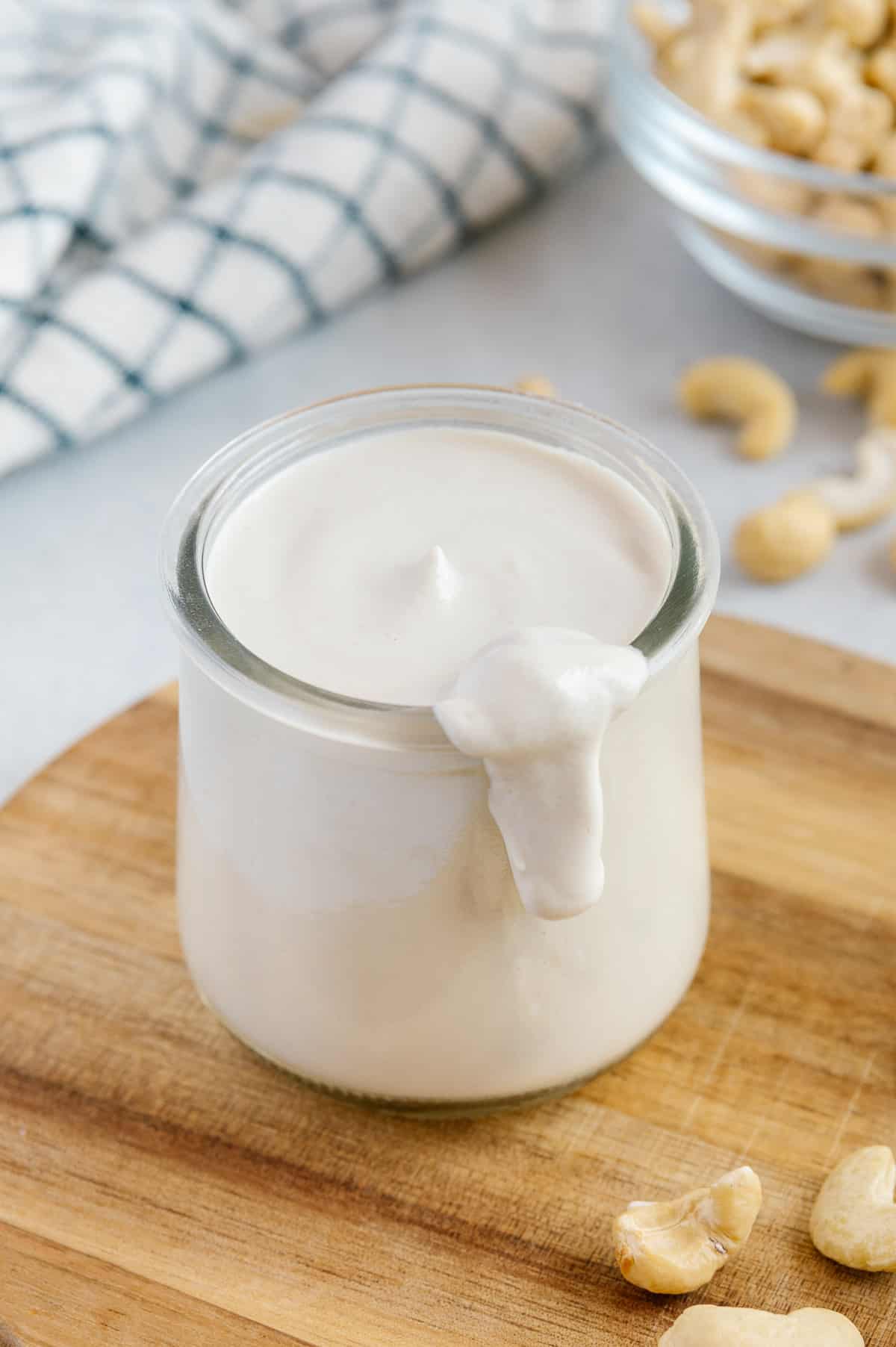 A glass jar filled with cashew cream spilling over the top.