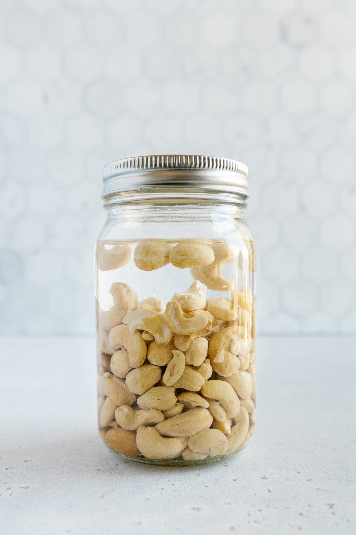 Raw cashews in a mason jar soaking in water.